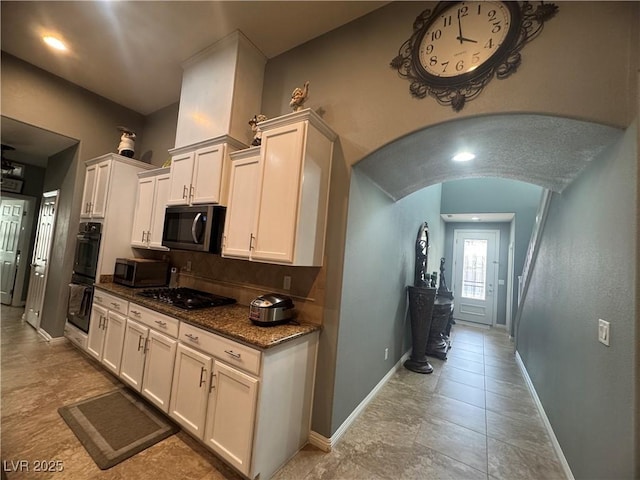 640 House Blend Ln, Henderson, NV 89052 - kitchen featuring black appliances, arched walkways, backsplash, baseboards, and white cabinetry