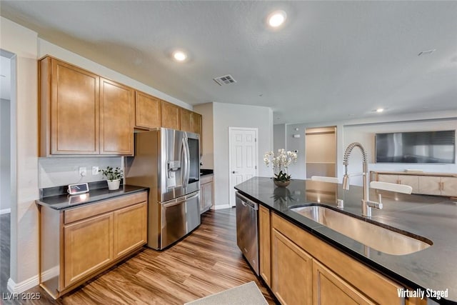 kitchen with stainless steel appliances, a sink, wood finished floors, baseboards, and recessed lighting