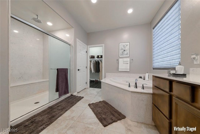 full bath featuring a stall shower, a bath, a spacious closet, recessed lighting, and vanity