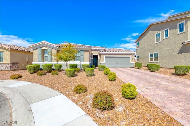 mediterranean / spanish-style house with decorative driveway, an attached garage, stucco siding, and a tile roof