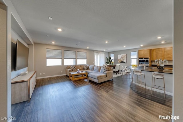 living area featuring dark wood-style flooring, baseboards, and recessed lighting