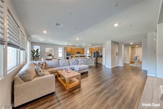 living area featuring recessed lighting, plenty of natural light, dark wood-style floors, and baseboards