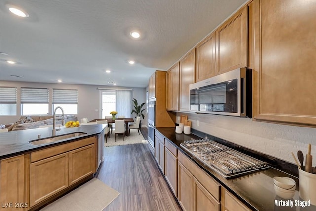 kitchen featuring appliances with stainless steel finishes, a sink, dark wood-type flooring, recessed lighting, and open floor plan