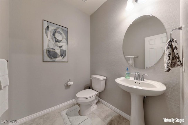 half bath featuring toilet and baseboards