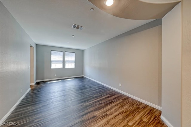 spare room featuring dark wood-style flooring and baseboards