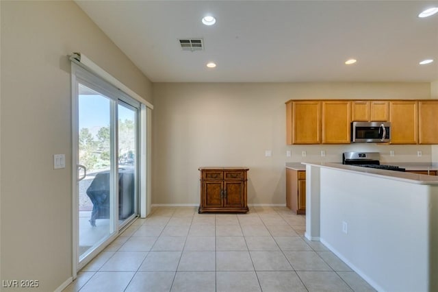 kitchen with stainless steel appliances, recessed lighting, baseboards, light countertops, and light tile patterned floors