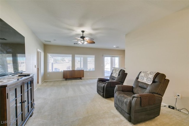 living area with light carpet, ceiling fan, and baseboards