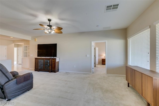 living area with ceiling fan, baseboards, and light colored carpet