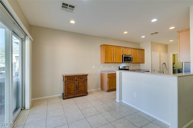 kitchen with stainless steel appliances, baseboards, recessed lighting, light countertops, and brown cabinets
