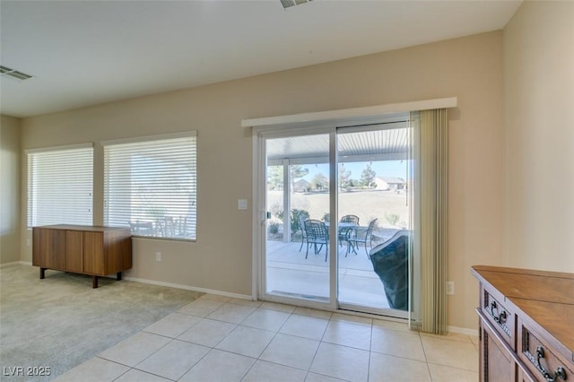 doorway with baseboards, light carpet, and light tile patterned flooring