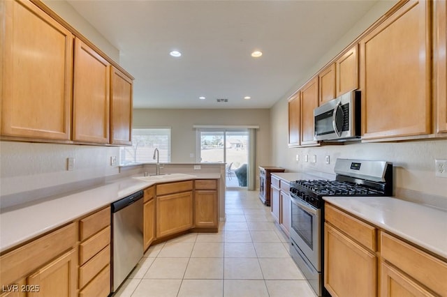 kitchen with appliances with stainless steel finishes, a sink, light countertops, recessed lighting, and a peninsula