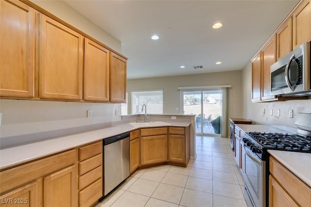 kitchen featuring stainless steel appliances, a sink, light countertops, recessed lighting, and a peninsula