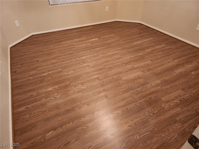 unfurnished room with dark wood-type flooring and baseboards