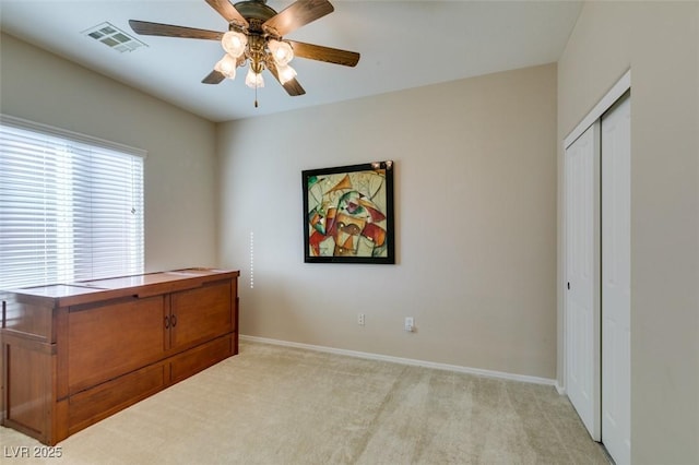 bedroom featuring light carpet, a closet, baseboards, and ceiling fan