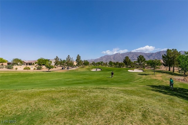 view of home's community with a yard, golf course view, and a mountain view