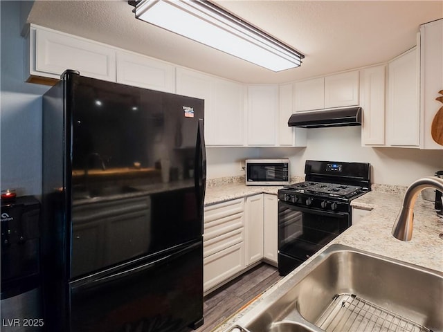 3771 Desert Marina Dr Unit 95, Laughlin, NV 89029 - kitchen with black appliances, under cabinet range hood, white cabinetry, wood finished floors, and light stone countertops