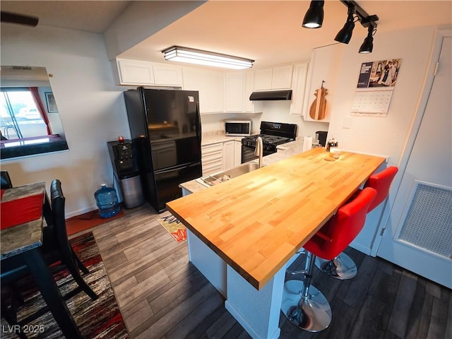 3771 Desert Marina Dr Unit 95, Laughlin, NV 89029 - kitchen with black appliances, under cabinet range hood, dark wood-style floors, a peninsula, and white cabinetry