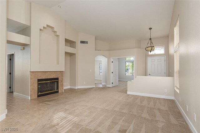 9404 Calico Garden Ave, Las Vegas, NV 89134 - unfurnished living room with high vaulted ceiling, baseboards, a fireplace, arched walkways, and light tile patterned floors