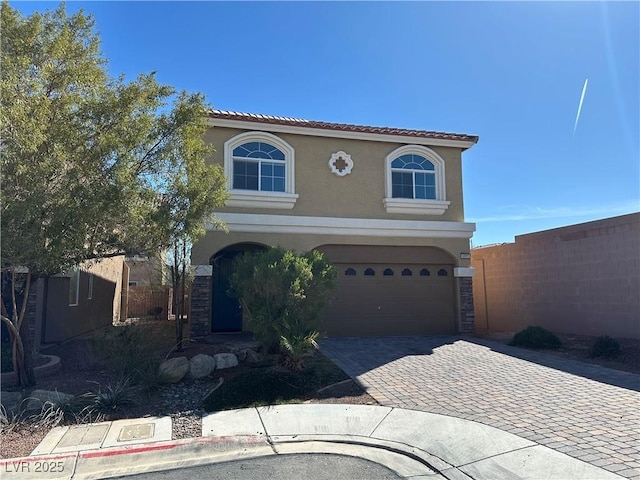 view of front of property with stucco siding, decorative driveway, an attached garage, a tile roof, and stone siding
