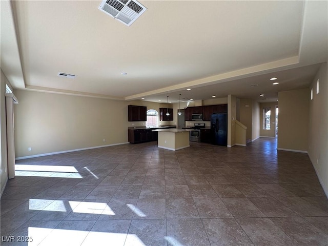unfurnished living room with baseboards, recessed lighting, and a raised ceiling