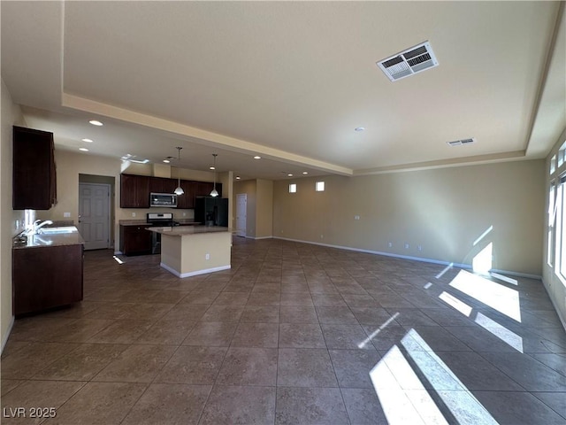 unfurnished living room featuring baseboards, a sink, recessed lighting, a tray ceiling, and dark tile patterned flooring