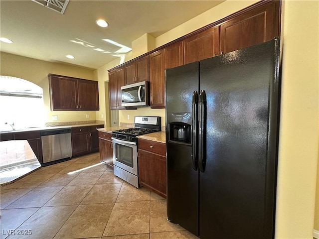 kitchen with appliances with stainless steel finishes, light tile patterned floors, light countertops, recessed lighting, and dark brown cabinets