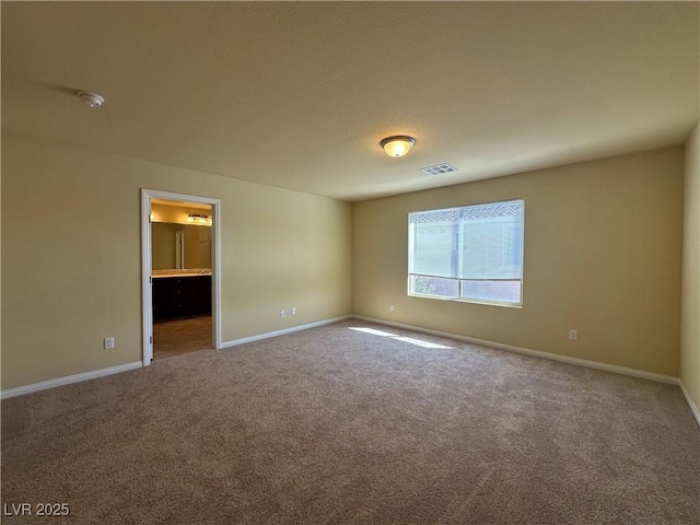 unfurnished bedroom with carpet flooring, baseboards, and ensuite bathroom