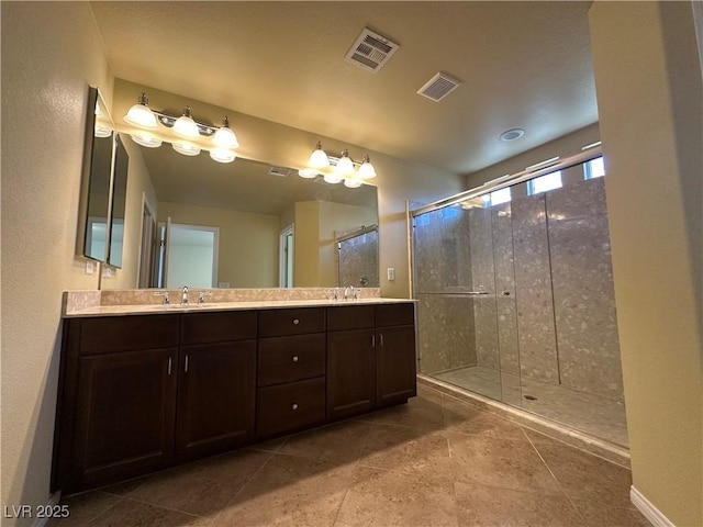 bathroom with a shower stall and double vanity
