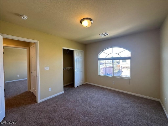 unfurnished bedroom with carpet flooring, a closet, baseboards, and a textured ceiling
