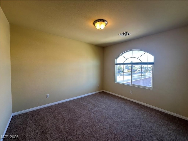 empty room with dark colored carpet and baseboards