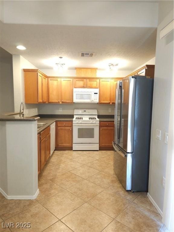4675 Basilicata Ln Unit 103, North Las Vegas, NV 89084 - kitchen with white appliances, dark countertops, light tile patterned floors, and baseboards