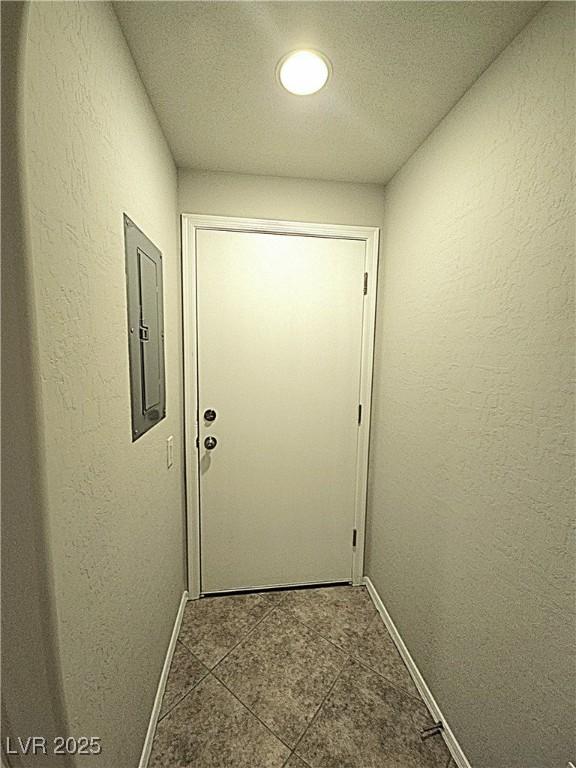 4675 Basilicata Ln Unit 103, North Las Vegas, NV 89084 - entryway featuring baseboards, electric panel, dark tile patterned flooring, a textured wall, and a textured ceiling