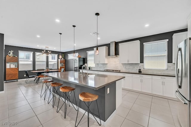 6834 Fallen Rock St, North Las Vegas, NV 89084 - kitchen featuring stainless steel appliances, wall chimney range hood, decorative backsplash, a sink, and light tile patterned floors