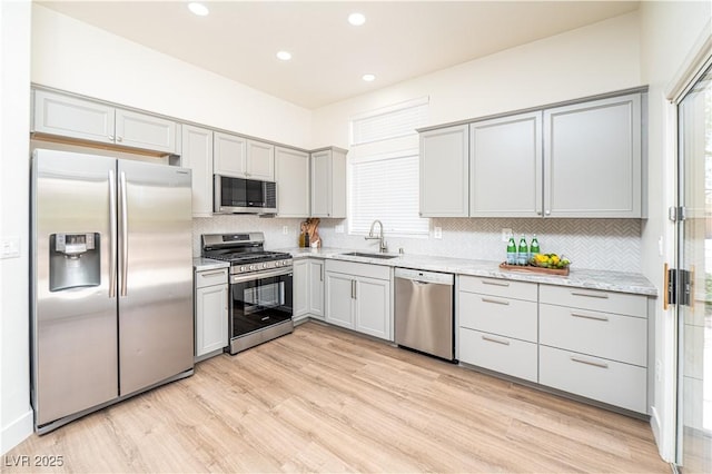 10301 Coal Creek Pl, Las Vegas, NV 89134 - kitchen featuring appliances with stainless steel finishes, gray cabinetry, decorative backsplash, light wood-style floors, and recessed lighting