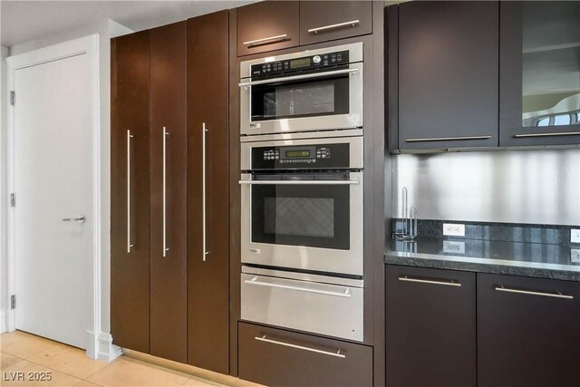 2700 S Las Vegas Blvd Unit 4305, Las Vegas, NV 89109 - kitchen with a warming drawer, double oven, light tile patterned floors, dark stone counters, and glass insert cabinets