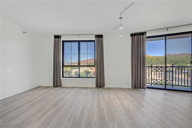 spare room with wood finished floors, plenty of natural light, and a mountain view