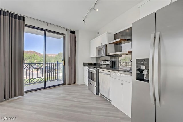 kitchen with stainless steel appliances, track lighting, white cabinets, light wood finished floors, and open shelves