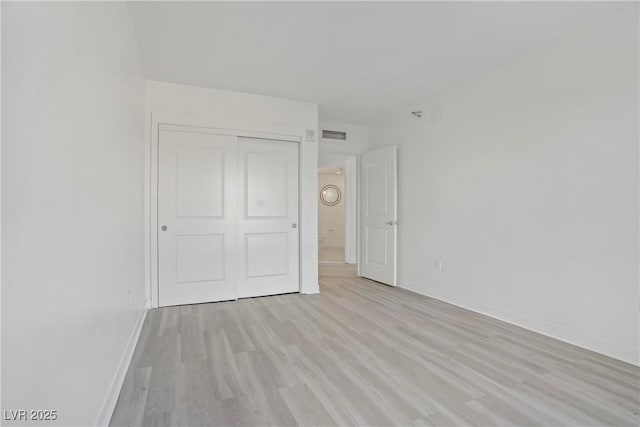 unfurnished bedroom with baseboards, light wood-type flooring, and a closet