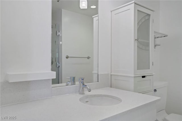 bathroom featuring toilet, vanity, and a shower with shower door