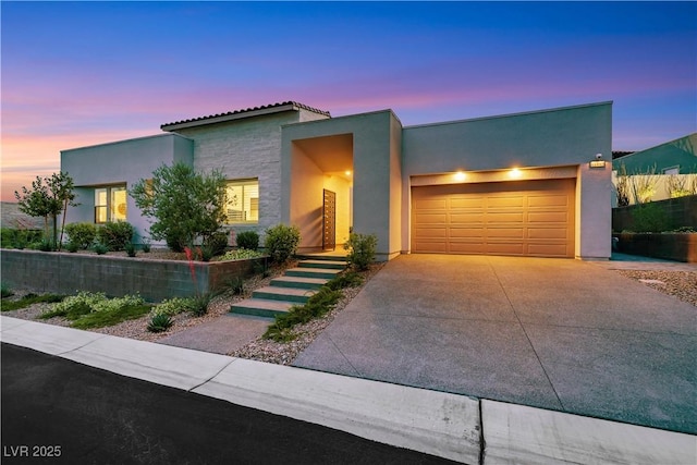 11895 Skyline Arch Ct, Las Vegas, NV 89138 - contemporary house with stucco siding, a garage, concrete driveway, a tile roof, and stone siding