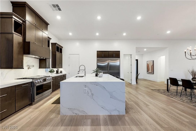 11895 Skyline Arch Ct, Las Vegas, NV 89138 - kitchen with high end appliances, a sink, light wood finished floors, a chandelier, and dark brown cabinets