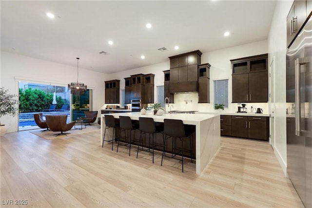 11895 Skyline Arch Ct, Las Vegas, NV 89138 - kitchen with light countertops, light wood-type flooring, a kitchen bar, a spacious island, and recessed lighting