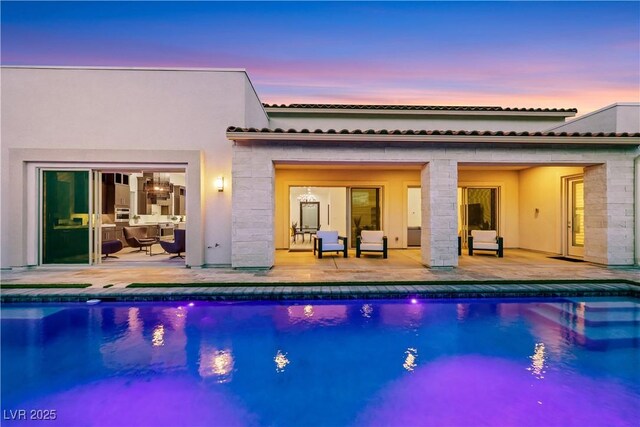 11895 Skyline Arch Ct, Las Vegas, NV 89138 - back of property with a patio, an outdoor pool, a tiled roof, and stucco siding