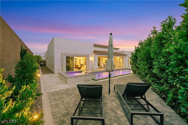 11895 Skyline Arch Ct, Las Vegas, NV 89138 - back of house at dusk featuring a patio area, an in-ground hot tub, stucco siding, and a pool