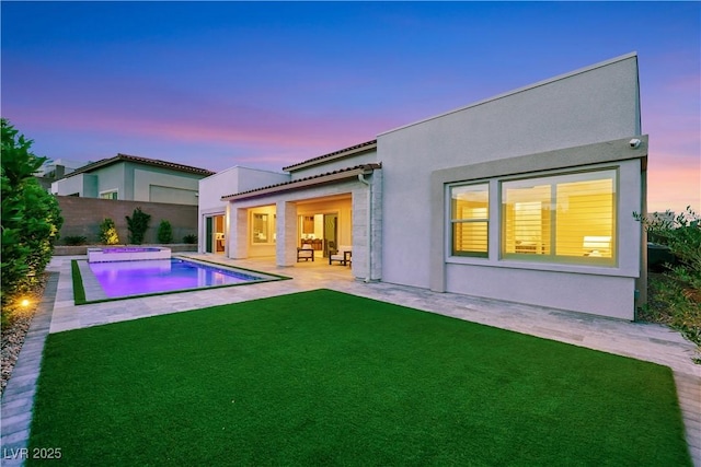 11895 Skyline Arch Ct, Las Vegas, NV 89138 - back of property at dusk with a patio area, stucco siding, and an in-ground hot tub