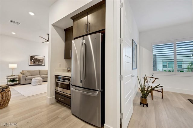 11895 Skyline Arch Ct, Las Vegas, NV 89138 - kitchen with appliances with stainless steel finishes, light wood finished floors, dark brown cabinetry, baseboards, and recessed lighting