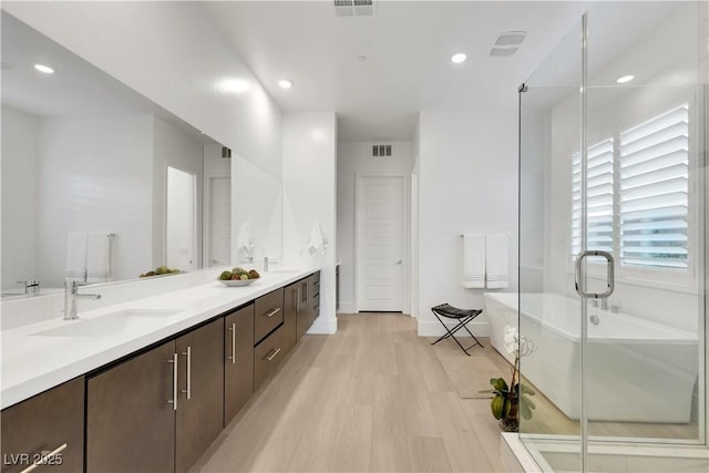 11895 Skyline Arch Ct, Las Vegas, NV 89138 - full bath with a freestanding tub, wood finished floors, double vanity, recessed lighting, and a shower stall