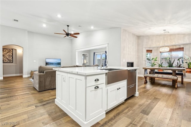 kitchen featuring dishwasher, ceiling fan, arched walkways, an island with sink, and open floor plan