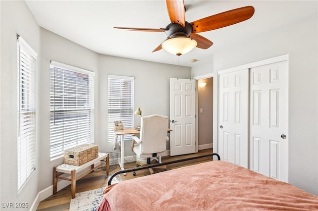 bedroom featuring a closet, baseboards, wood finished floors, and a ceiling fan
