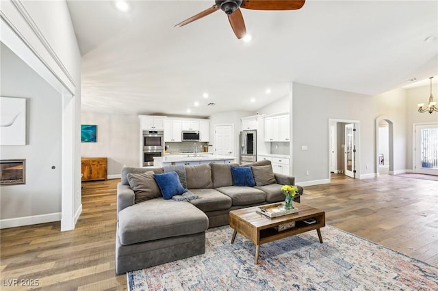 living area with ceiling fan, arched walkways, baseboards, light wood-type flooring, and recessed lighting